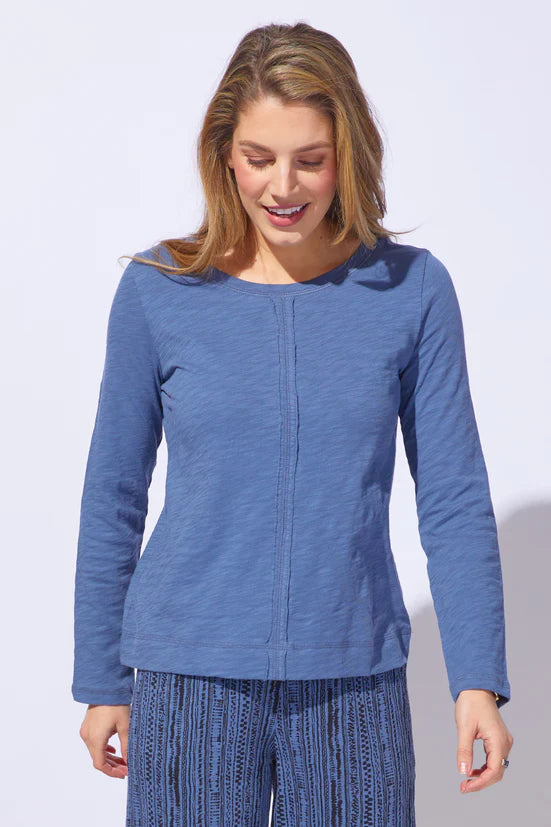 Woman wearing a blue long-sleeve top and pants on a light gray background