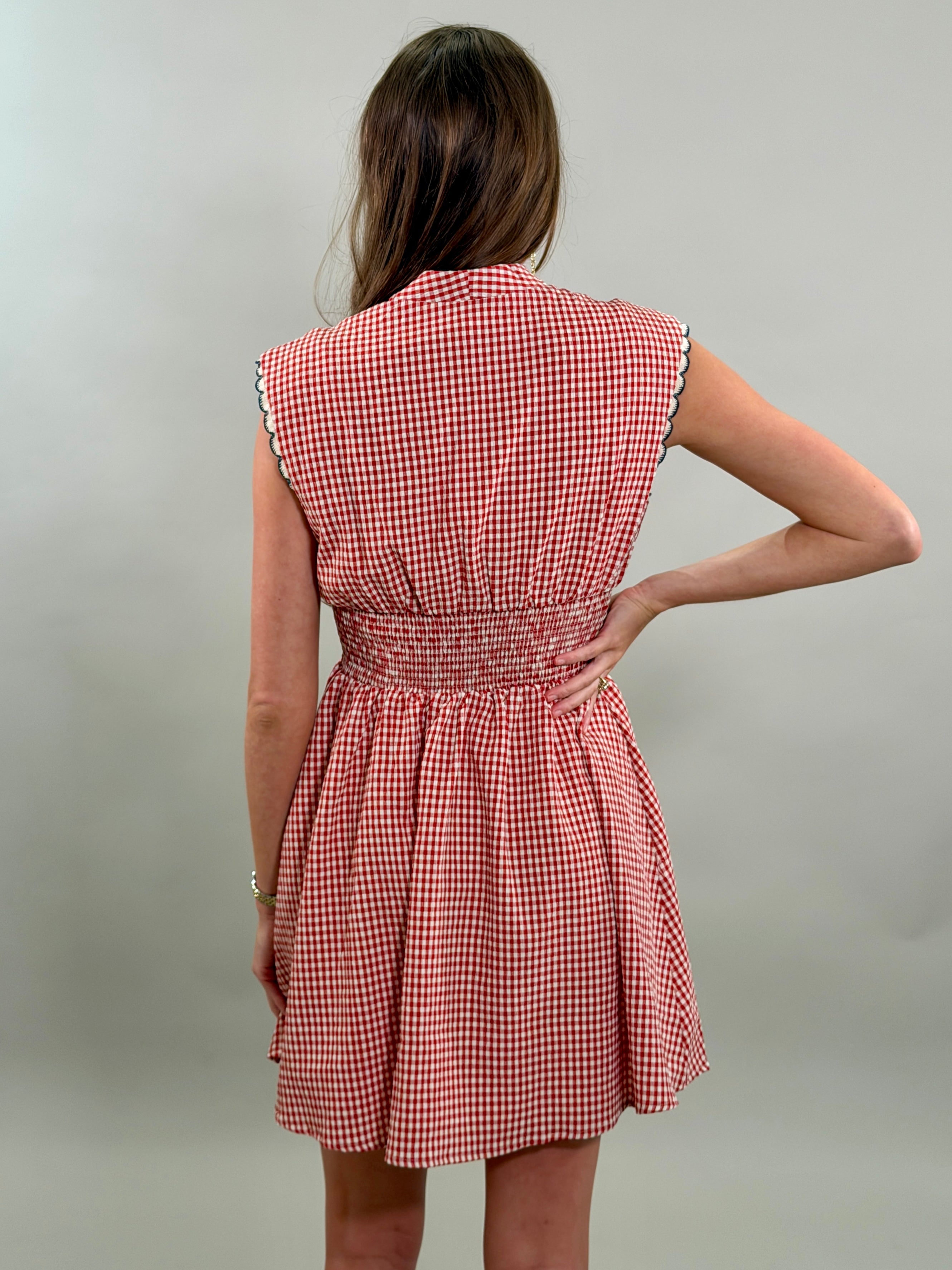 Rear view of a woman wearing a red and white checkered dress against a plain background
