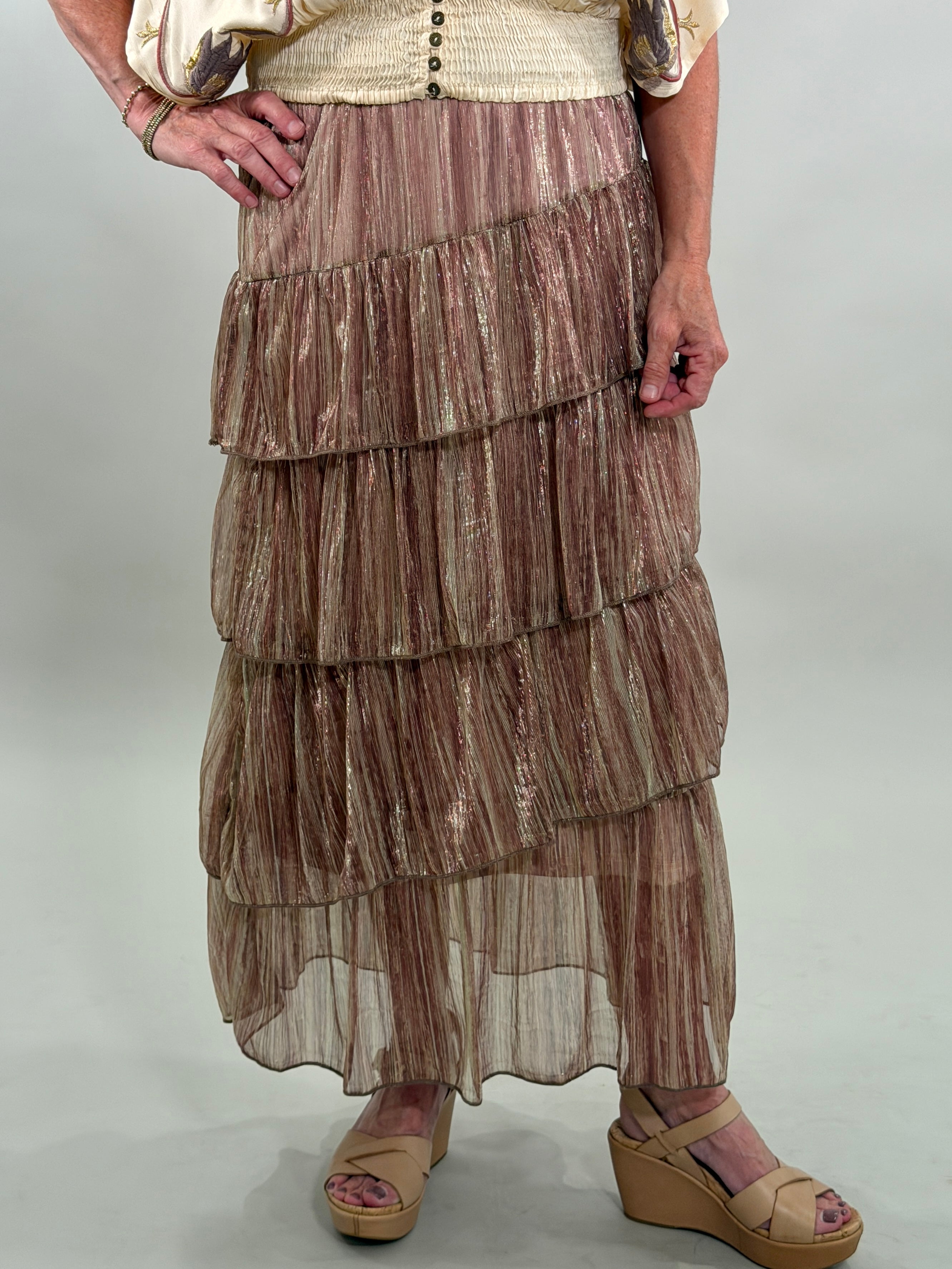 Close up of a woman wearing a layered, patterned skirt on a plain background