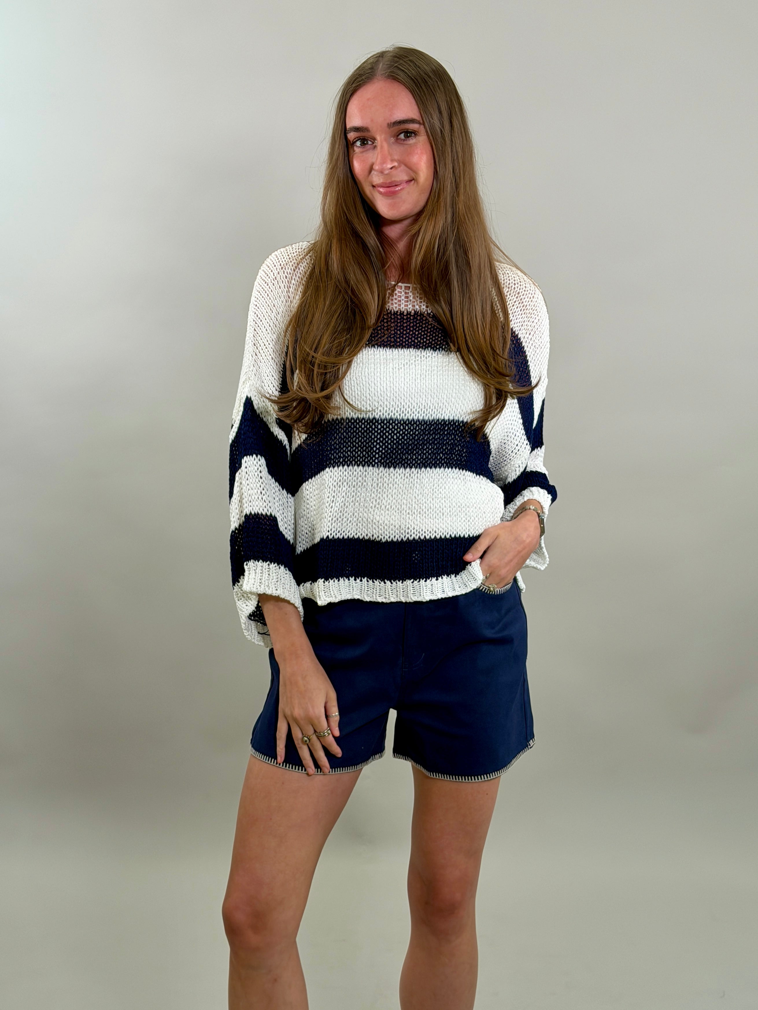 Woman wearing a striped sweater and shorts on a plain background