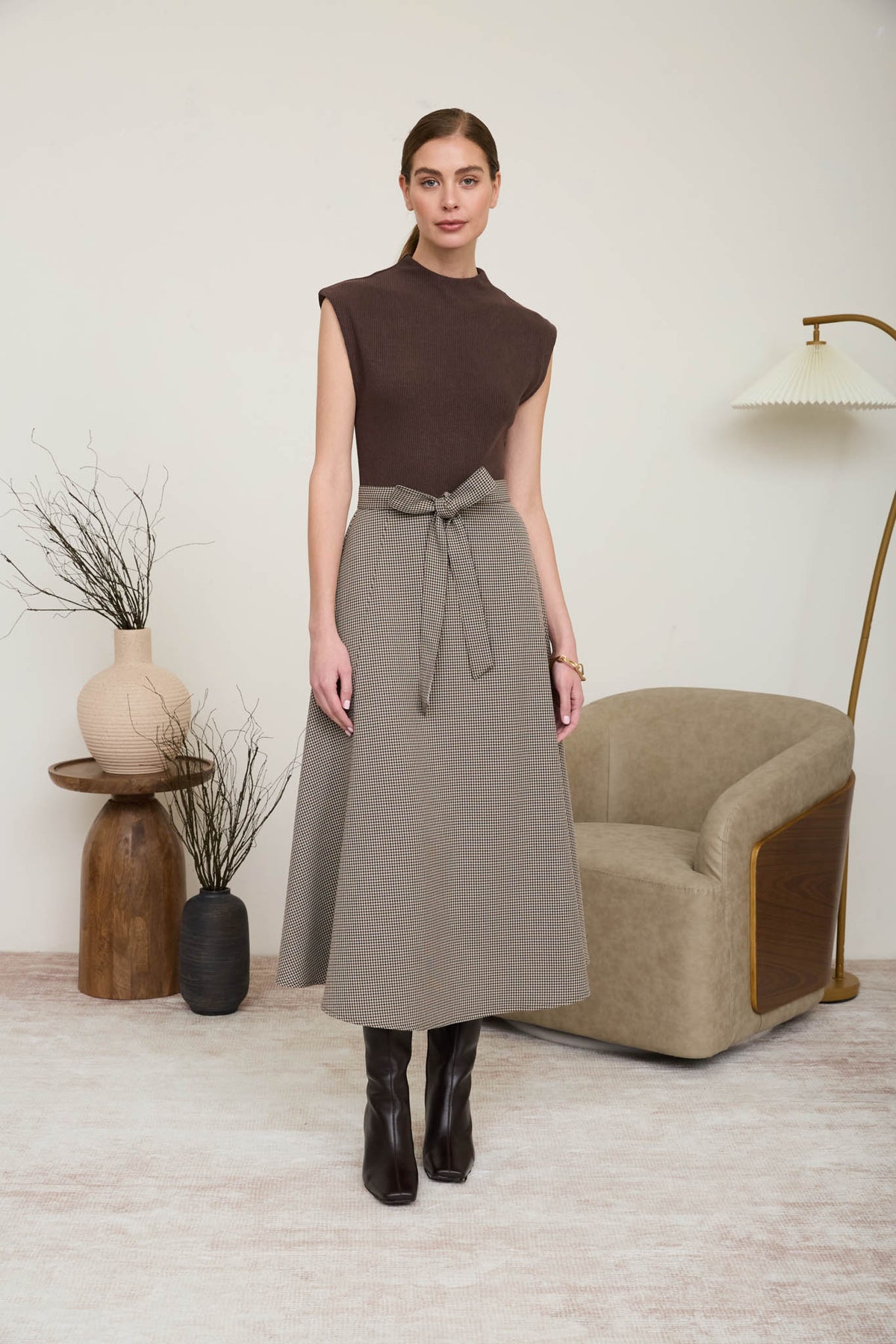 A woman wearing a sophisticated midi dress featuring a chocolate brown ribbed knit mock-neck top and a neutral houndstooth A-line skirt with a matching tie belt.