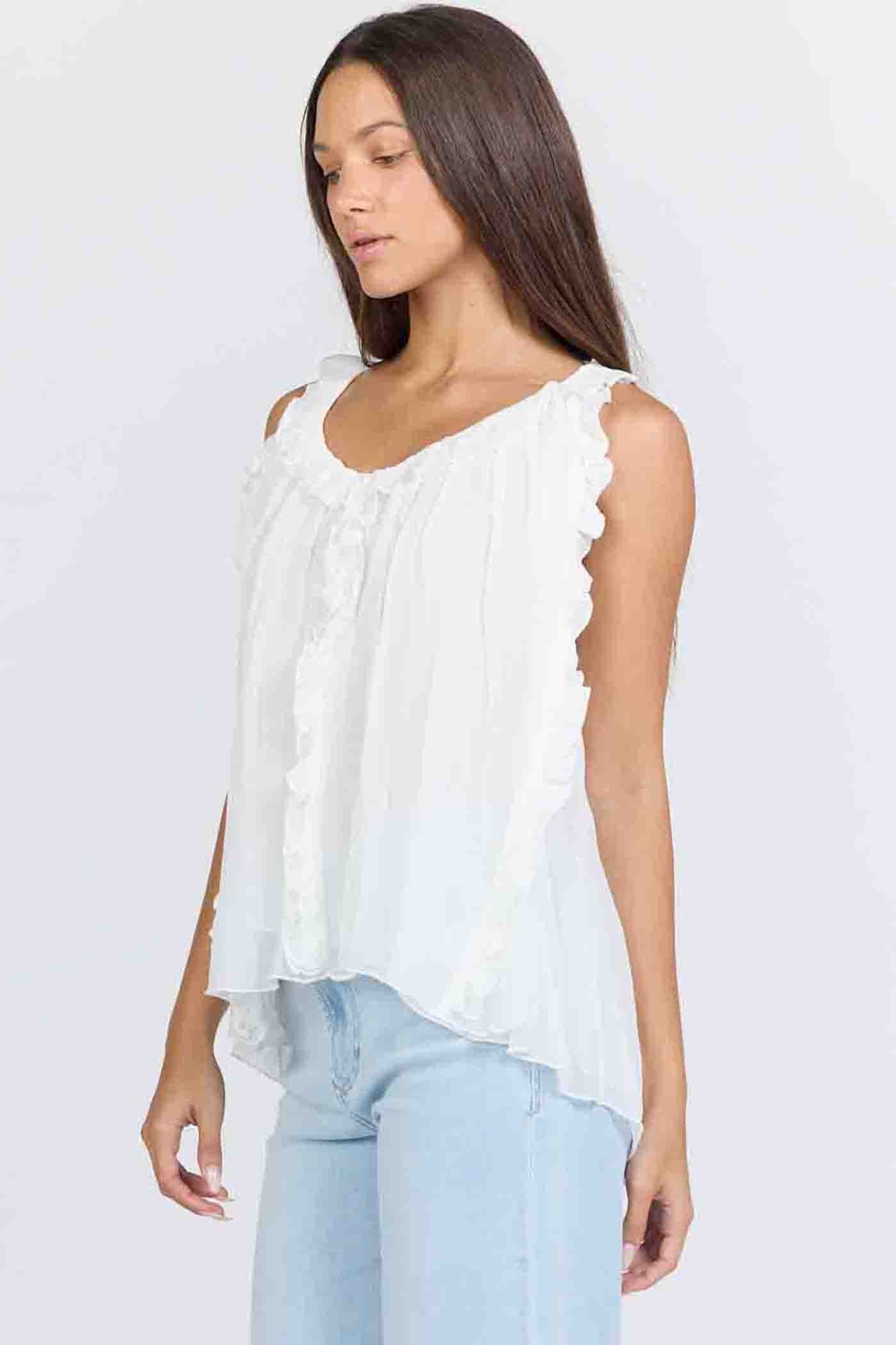 Side view of a woman wearing a flowy white sleeveless scoop-neck top with vertical ruffles and light blue jeans.