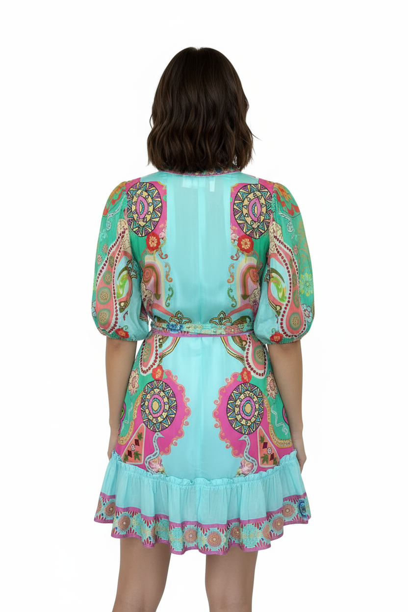 Rear view of a woman wearing a colorful turquoise paisley mini dress with puff sleeves and a matching tie waist belt.