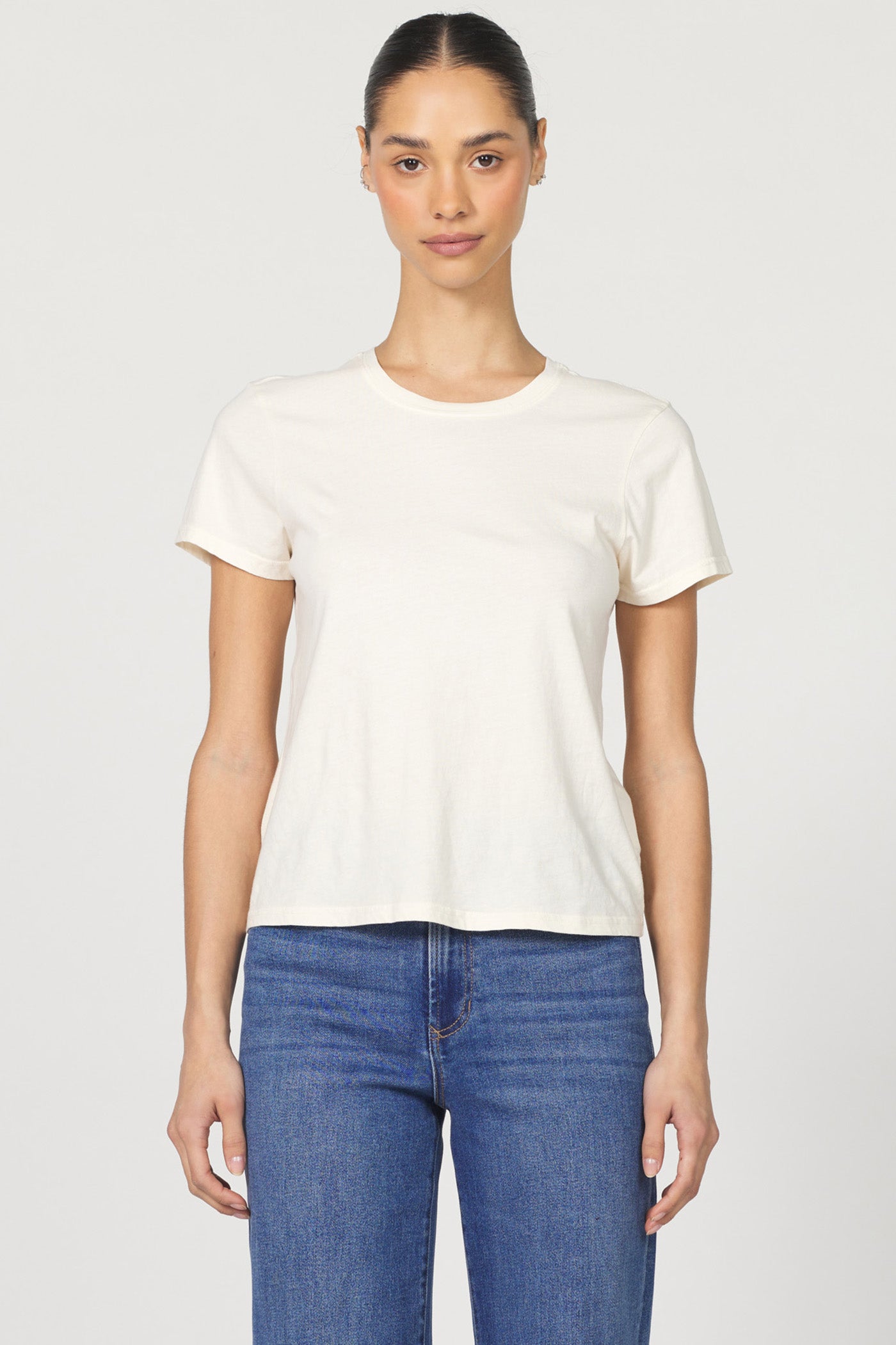 Front view of a woman wearing a white classic short-sleeve crew neck cotton jersey t-shirt paired with denim