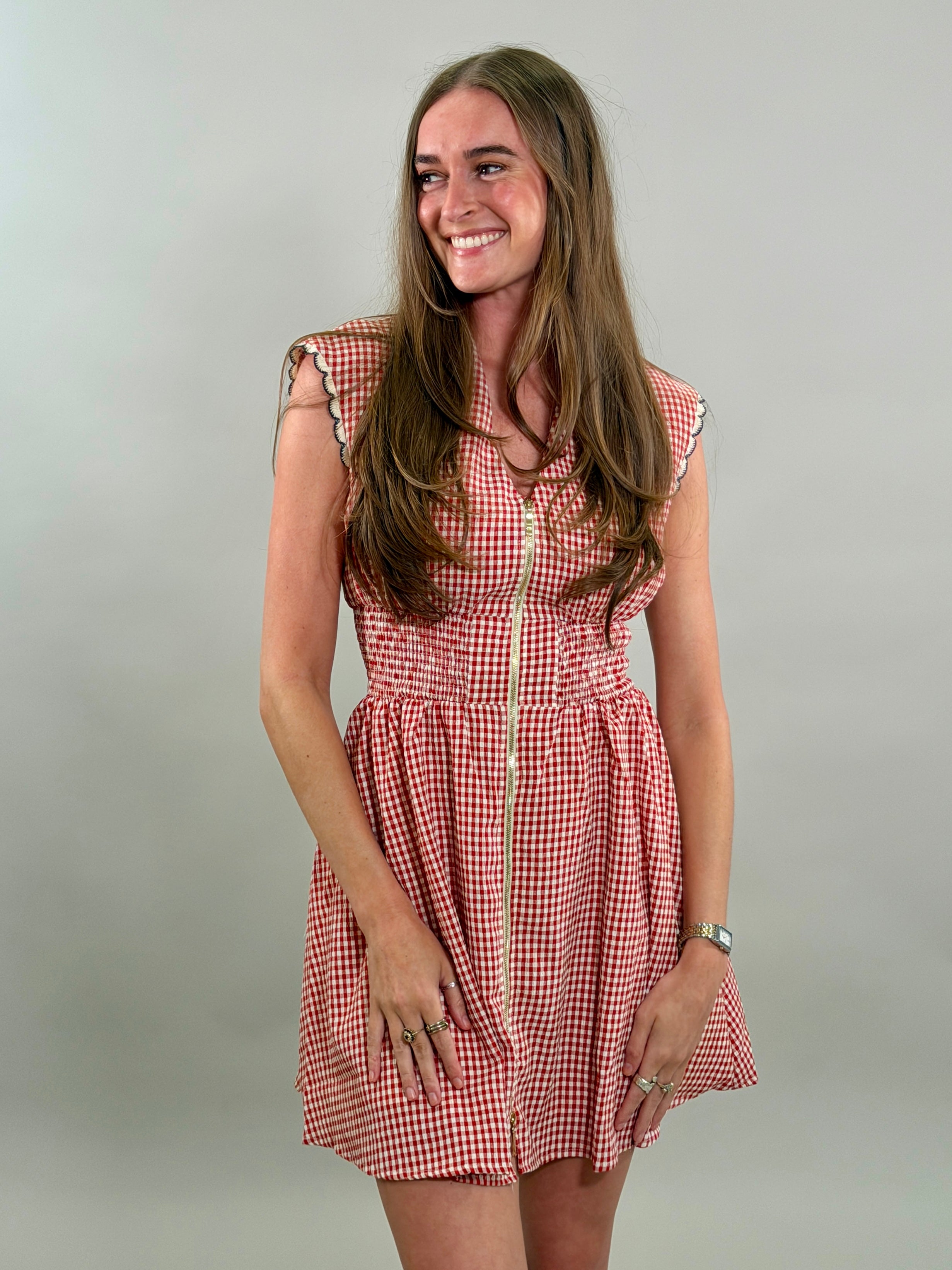 Woman looking to the side wearing a red and white checkered dress against a plain background