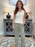 Woman wearing a cream ribbed scoop neck tank top with lace trim and olive green embroidered pants