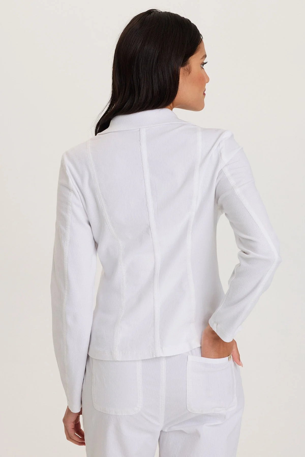 Rear view of a woman wearing a white suit on a plain background