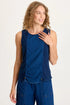 Front view of a woman with curly blonde hair wearing a dark indigo mixed-media tank top featuring adjustable front cinch cords and a raw-edge hem.