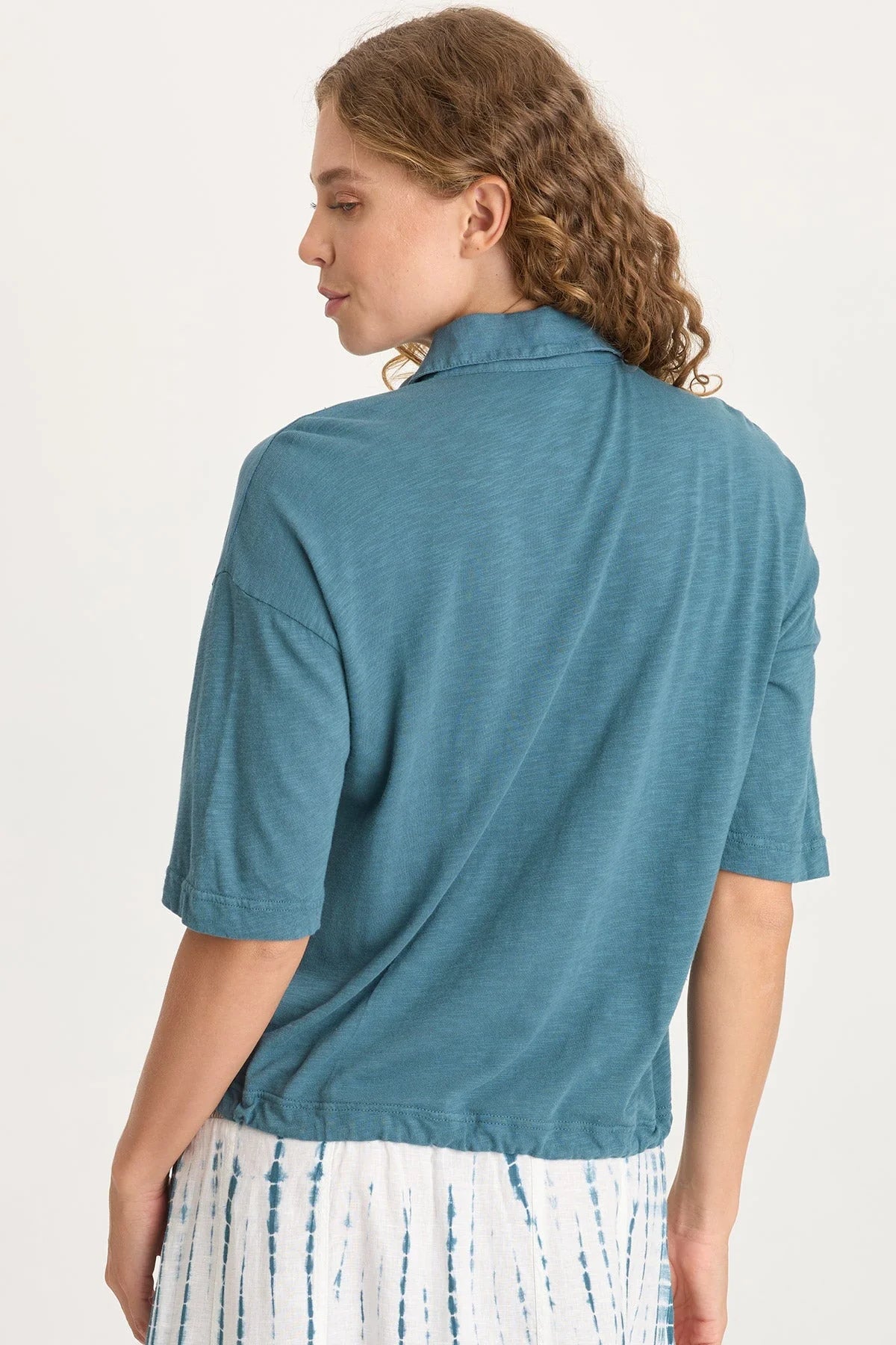 Rear view of a woman wearing a teal shirt with a white background