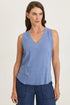 Woman wearing a light blue mixed-media sleeveless v-neck top with a frayed hem paired with navy blue pants.