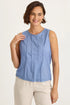 Woman wearing a blue sleeveless top and beige pants on a white background