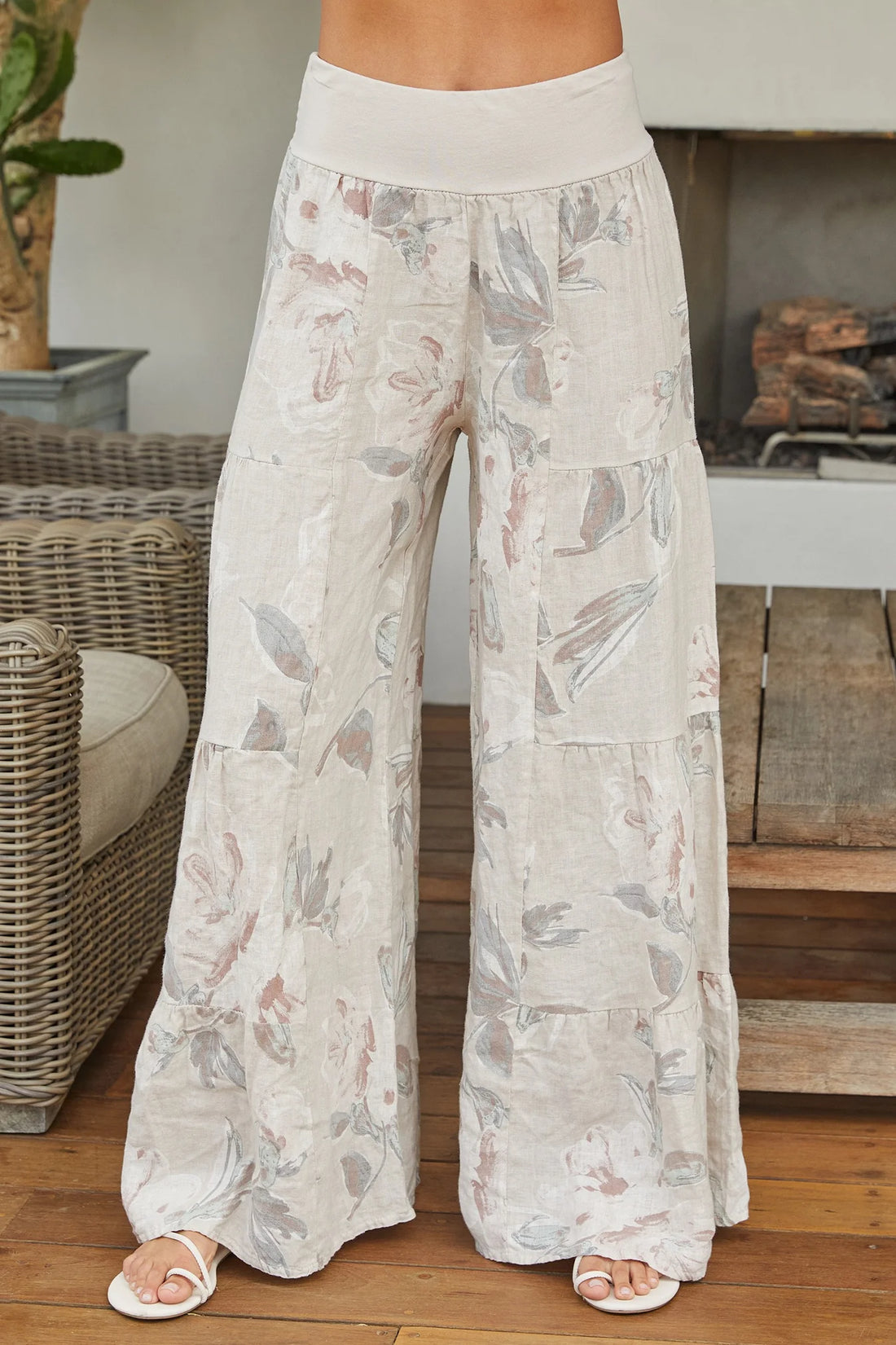 Person wearing floral-patterned wide-leg pants in a home setting.