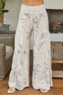 Person wearing floral-patterned wide-leg pants in a home setting.