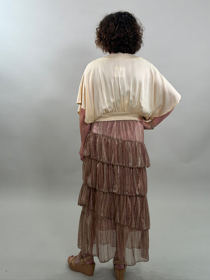 Rear view of a woman wearing a cream-colored bohemian blouse and a ruffled skirt with a smocked waist.