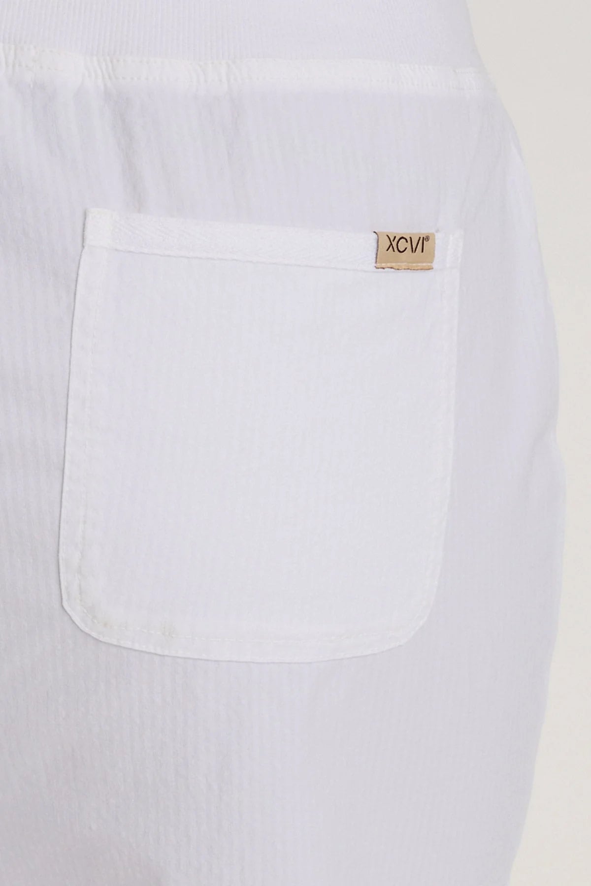 Close-up of a white pant with a brand label on the chest pocket.