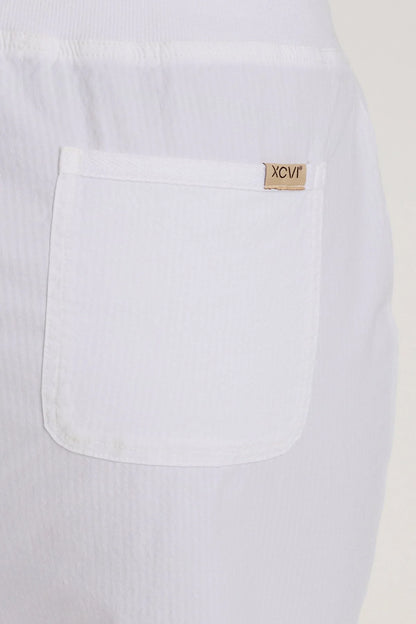 Close-up of a white pant with a brand label on the chest pocket.