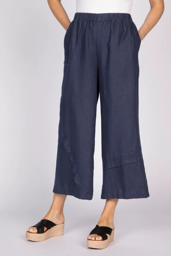 Front view of a woman wearing navy blue wide-leg linen pants with unique pleat details at the hem and black platform sandals