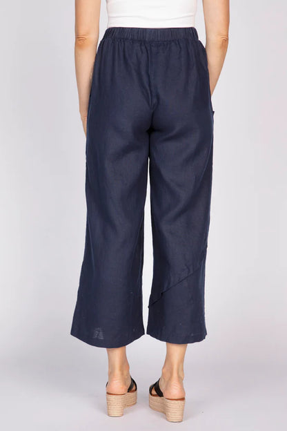 Rear view of a woman wearing navy blue wide-leg linen pants with unique pleat details at the hem