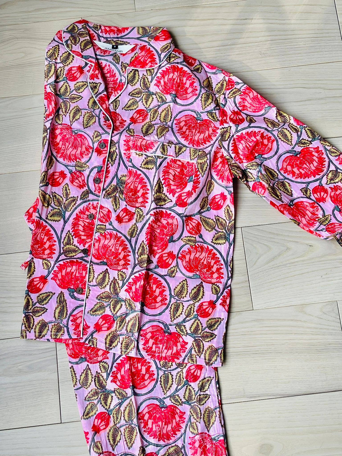 A pink and red floral hand-block printed 100% cotton pajama set with a button-down top and matching pants.