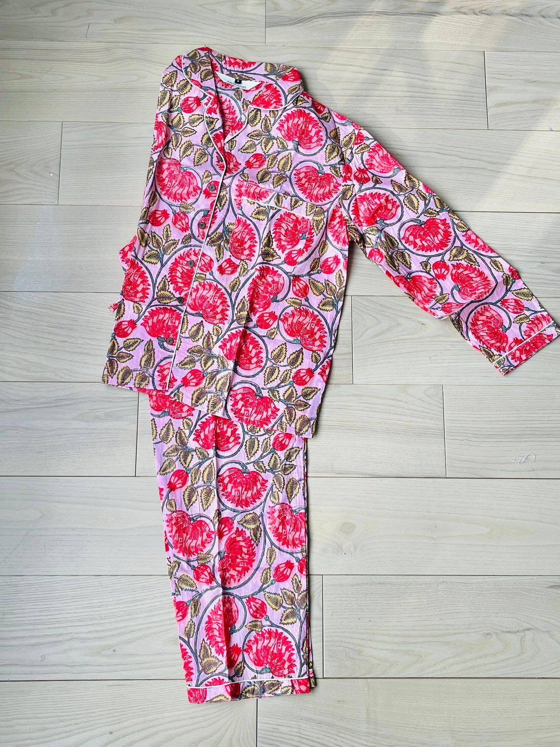 A pink and red floral hand-block printed 100% cotton pajama set with a button-down top and matching pants.
