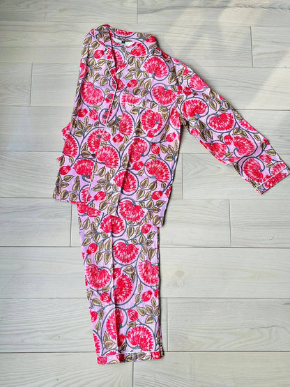 A pink and red floral hand-block printed 100% cotton pajama set with a button-down top and matching pants.