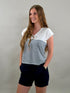 Woman wearing a white and navy striped shirt with navy shorts against a plain background