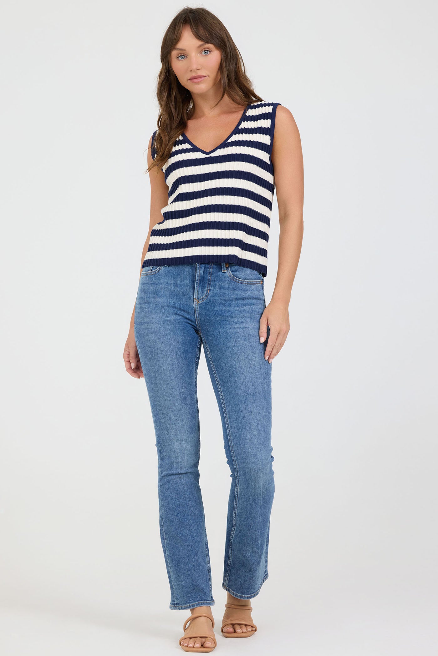 Full size view of a woman wearing a striped tank top and blue jeans on a white background