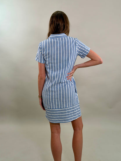 Rear view of a woman wearing a blue and white striped dress against a plain background