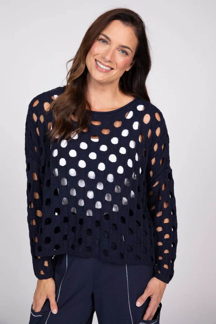 Front view of a woman wearing a navy blue open-knit cotton sweater over a white tank top.