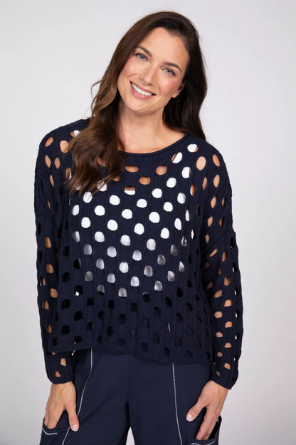 Front view of a woman wearing a navy blue open-knit cotton sweater over a white tank top.