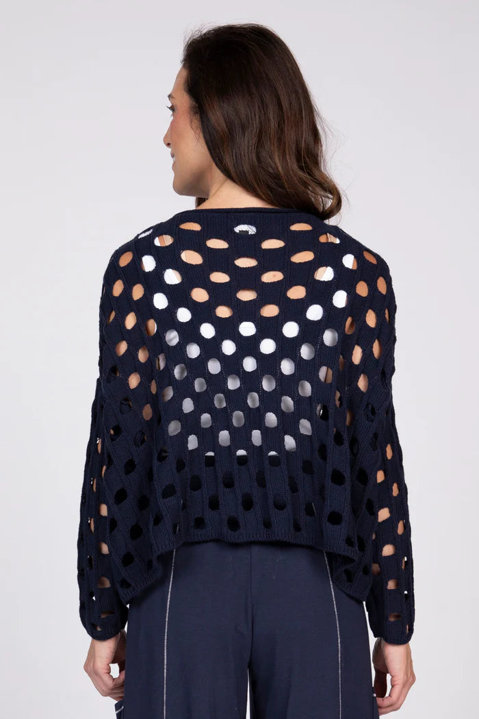Rear view of a woman wearing a navy blue open-knit cotton sweater over a white tank top.