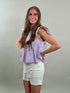 Side view of a woman wearing a striped top and white shorts against a plain background