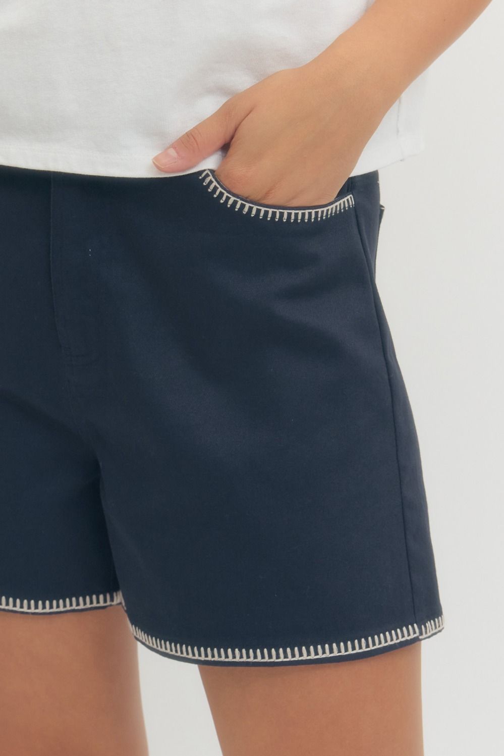 Navy shorts with white trim worn by a person on a white background
