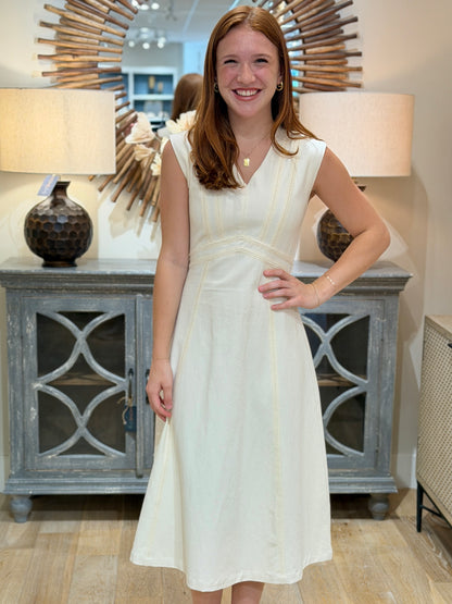 Close up of a young woman with reddish hair smiling while wearing an elegant cream cotton midi dress with vertical crochet insets.