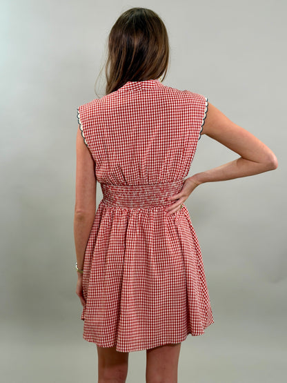 Rear view of a woman wearing a red and white checkered dress against a plain background