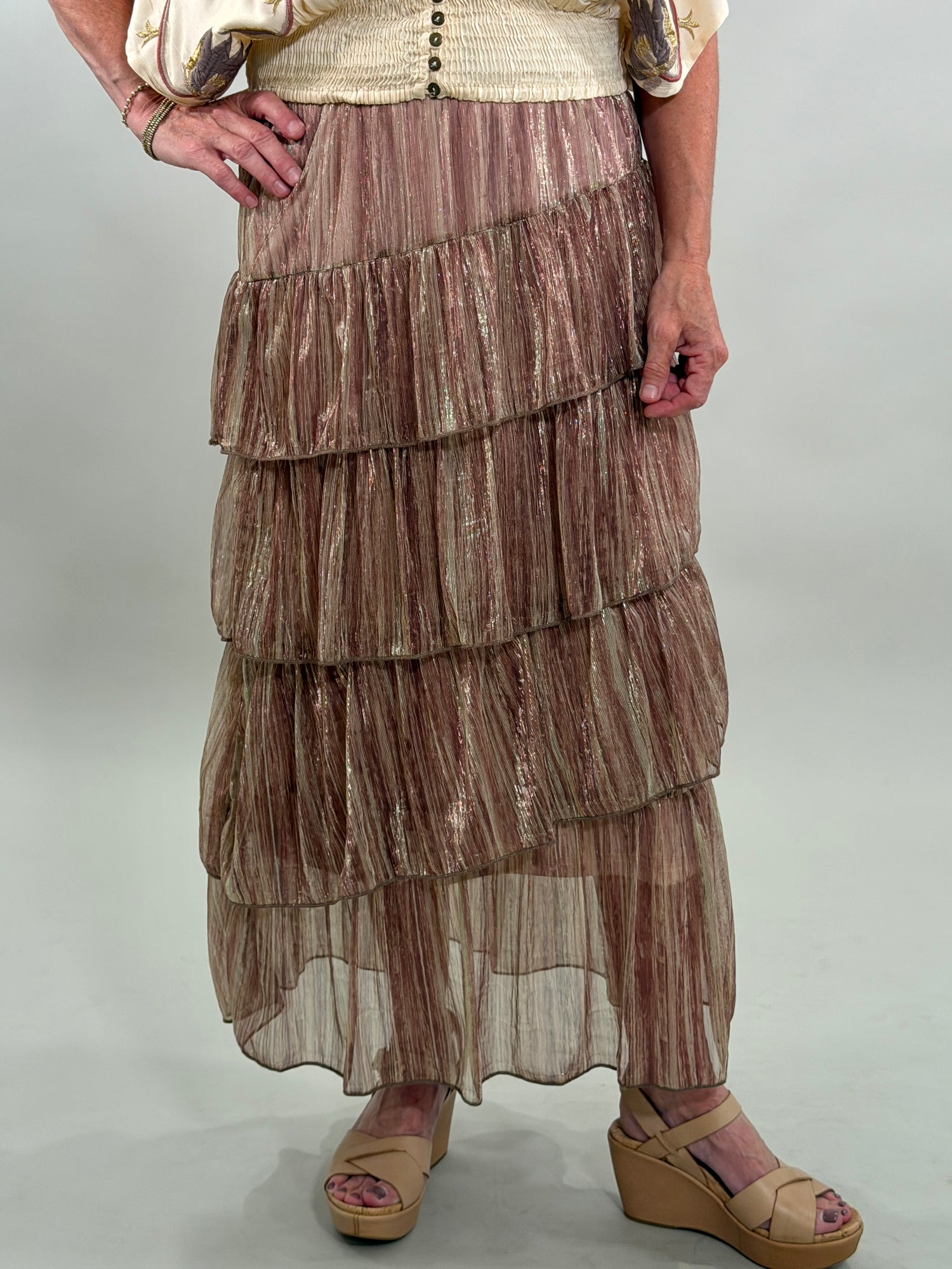Close up of a woman wearing a layered, patterned skirt on a plain background