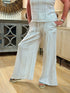 Close up of a woman wearing striped white and blue cotton gauze wide-leg pants with patch pockets, an elastic drawstring waist, and platform sandals.