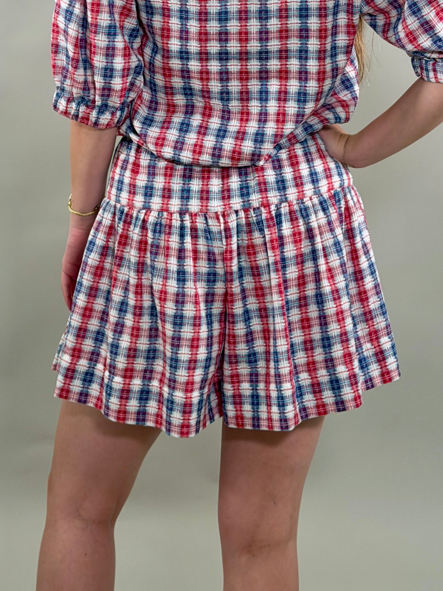 Person wearing a red, white, and blue plaid outfit on a plain background