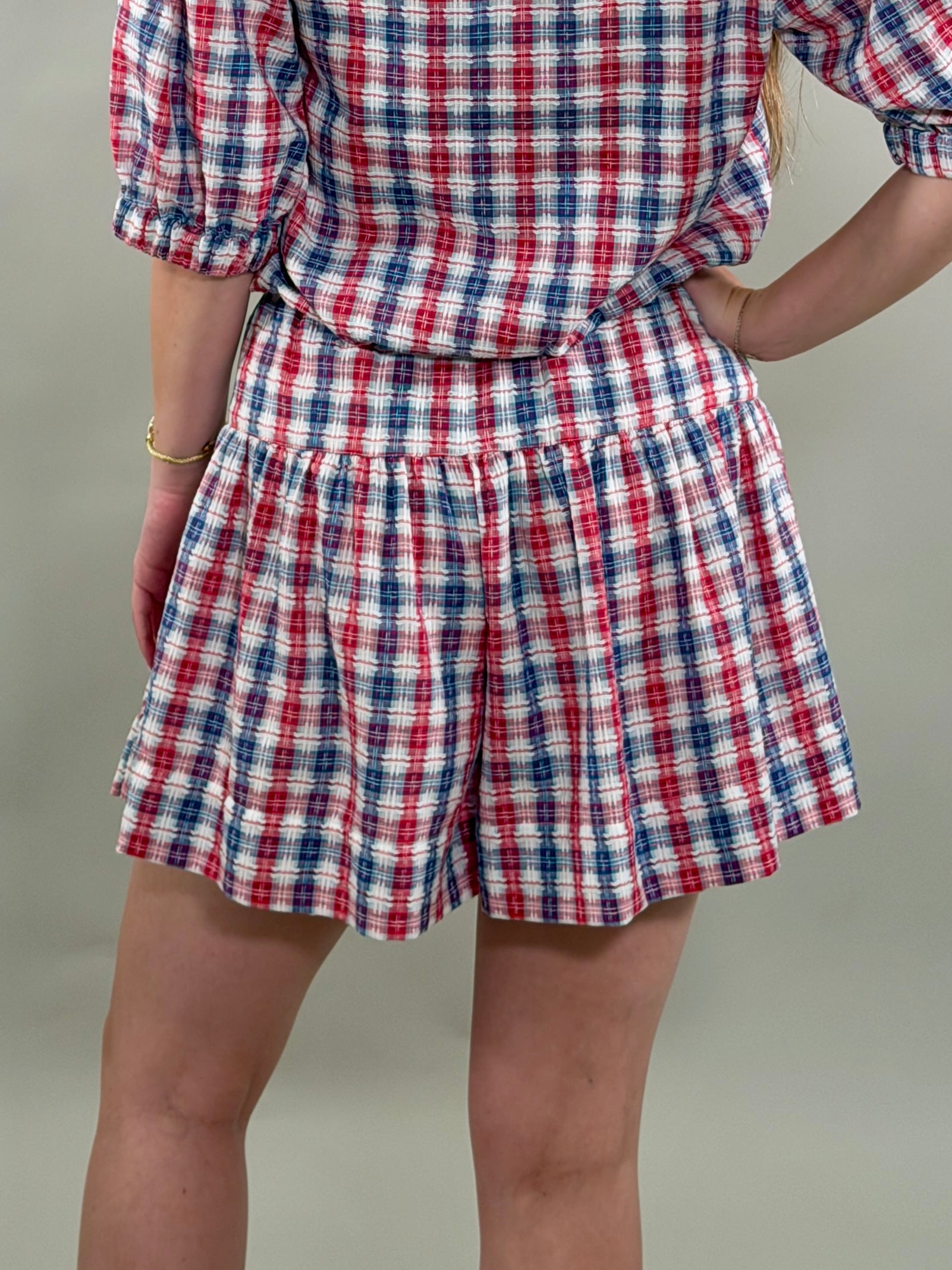 Person wearing a red, white, and blue plaid outfit on a plain background