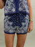 Close up view of navy blue and white paisley patterned top and shorts on a neutral background