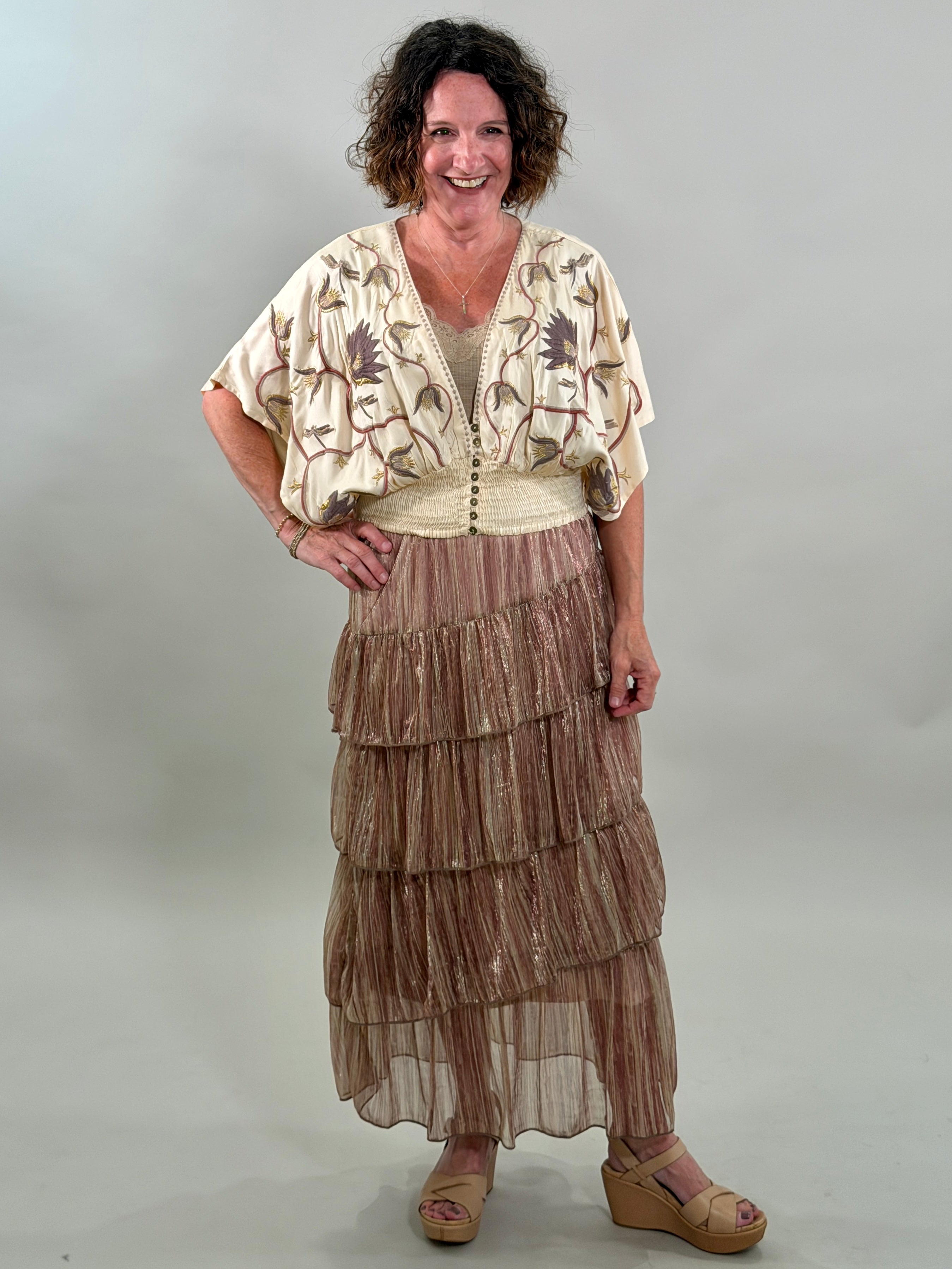 Woman wearing a layered skirt and patterned top against a plain background