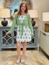 Woman wearing a green cardigan over a patterned dress in a home decor setting.