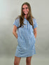 Woman wearing a blue and white striped dress against a plain background