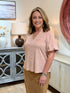 Woman wearing a blush pink faux-suede short-sleeve top with a notch neckline.