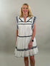 Woman wearing a white dress with navy trim against a plain background
