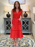 Woman wearing a tomato red sleeveless cotton midi dress with a removable belt and patch pockets.
