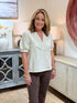 Woman wearing a cream faux-suede short-sleeve top with a notch neckline and leopard print pants.
