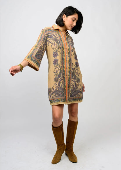 Woman wearing a patterned dress with bell sleeves and brown boots on a white background