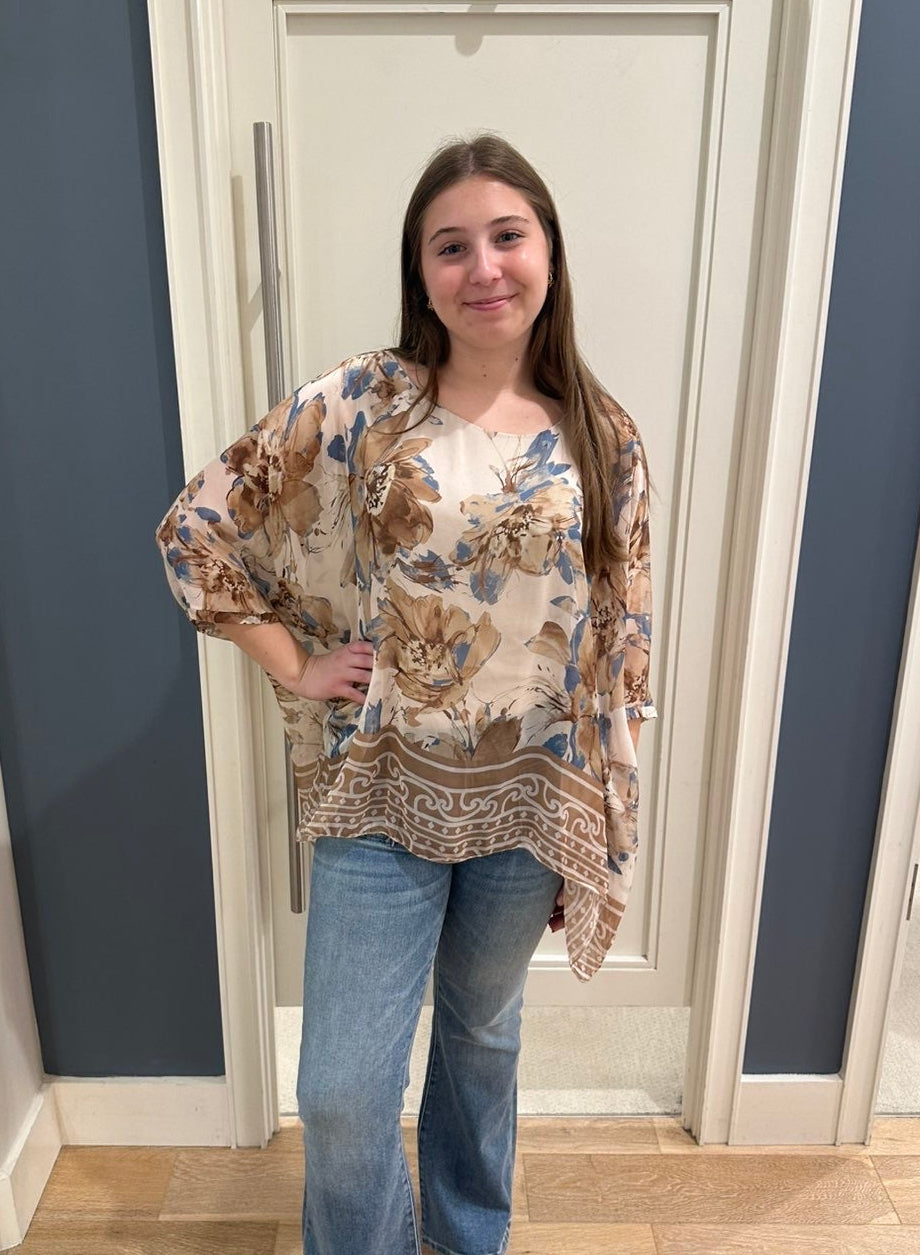 Woman wearing a floral blouse and jeans.