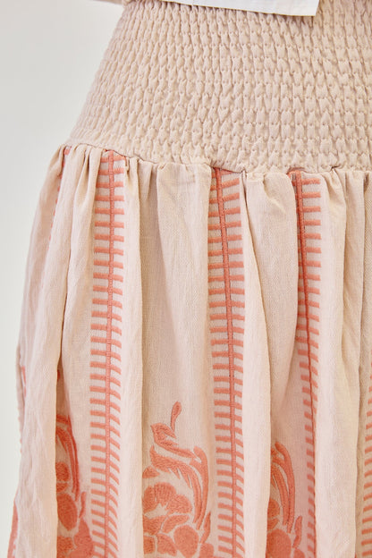 Close up of a skirt with coral pattern and smocked waist on a white background